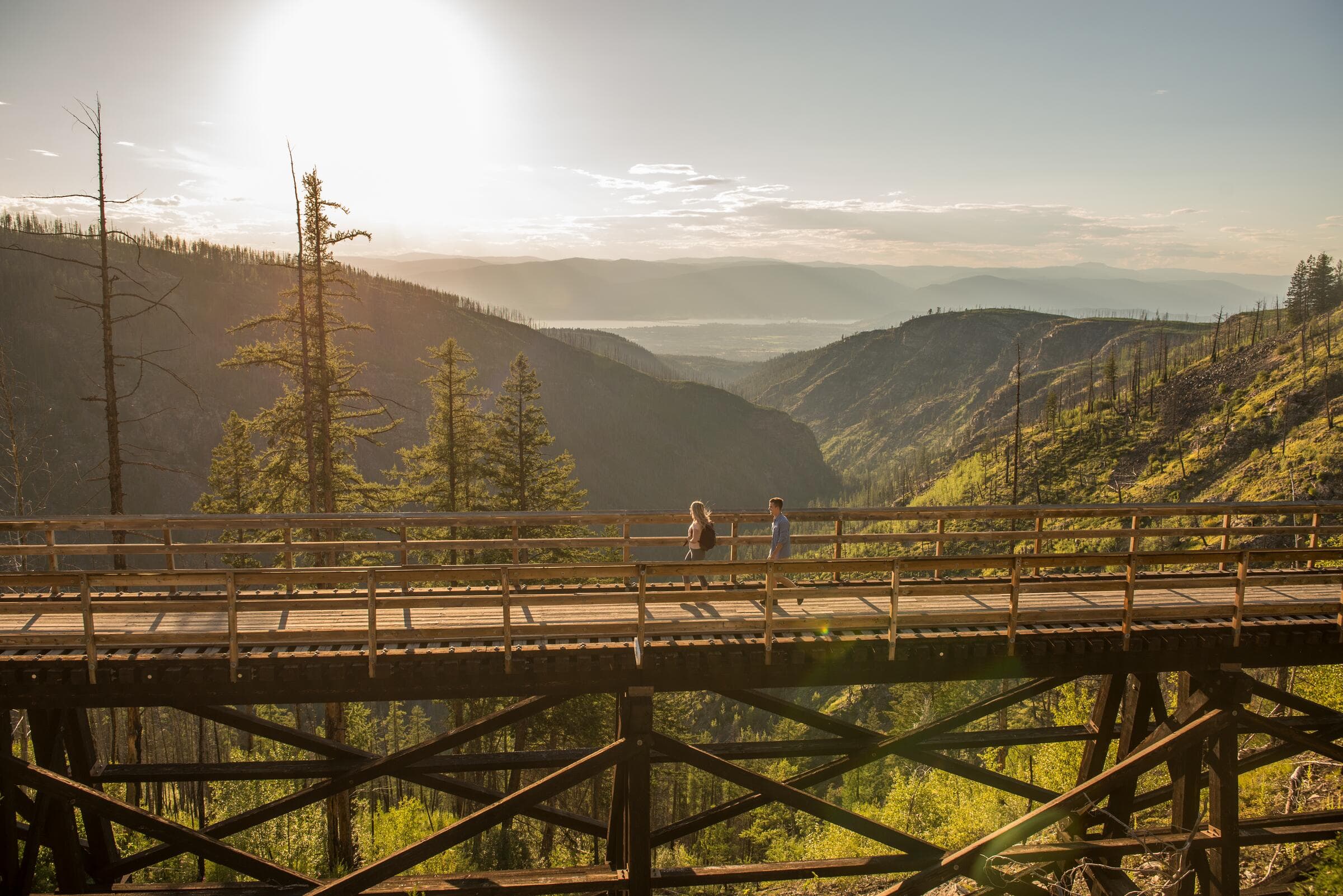 Two hikers crossing a wooden trestle above Myra Canyon