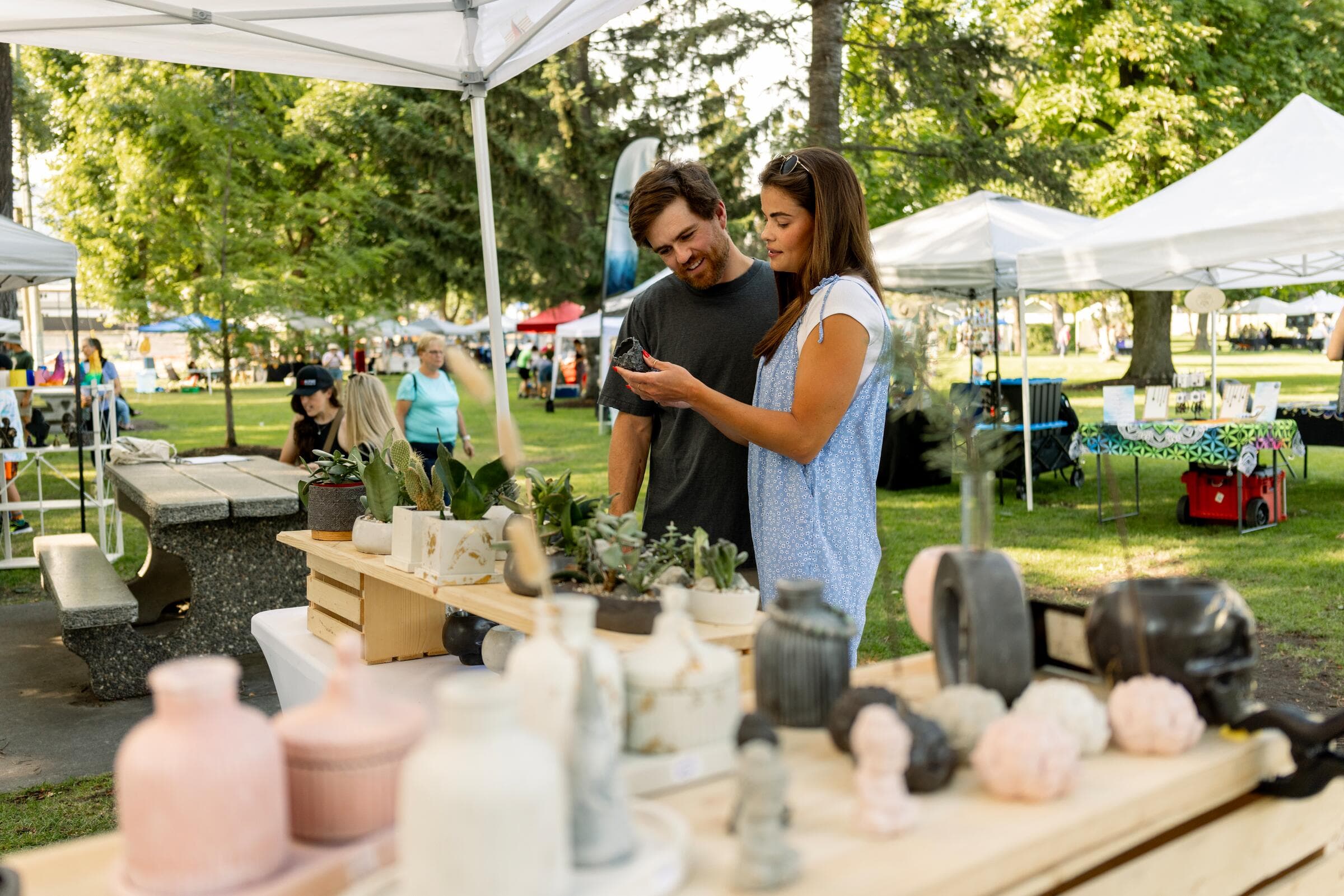 Two people browsing a stall at a farmers market in Vernon